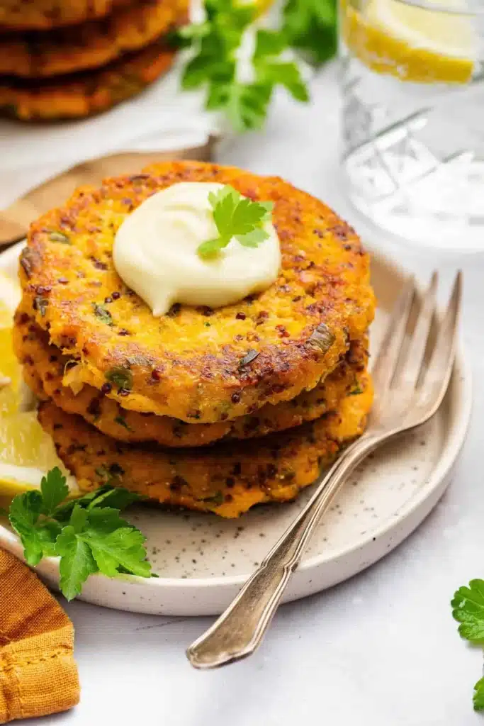 Plate of crispy salmon patties served with dipping sauce and garnished with herbs
