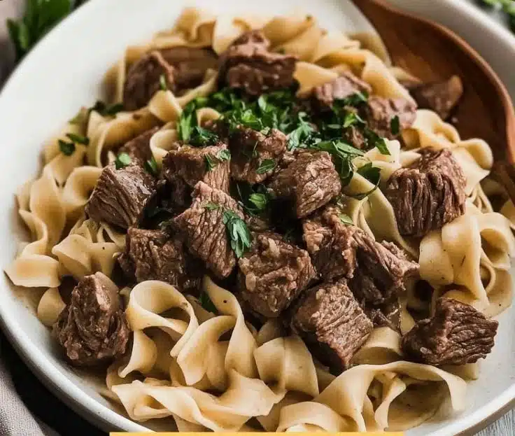 A bowl of delicious beef noodles topped with fresh herbs and spices.