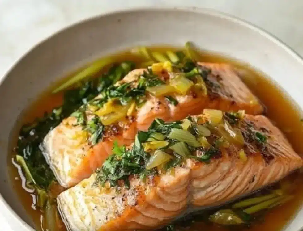 Delicious easy steamed ginger salmon served on a plate with herbs and vegetables.