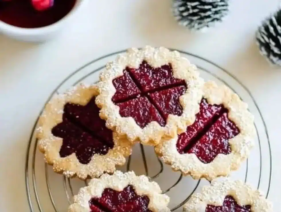 Freshly baked Raspberry Linzer Cookies dusted with powdered sugar.